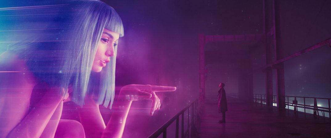 A giant hologram of Ana de Armas, as Joi, points at Ryan Gosling, as K