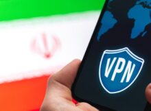 Hand holding a smartphone with a VPN logo on screen, the Iran