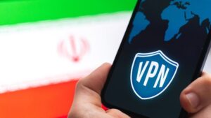 Hand holding a smartphone with a VPN logo on screen, the Iran