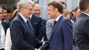 French President Emmanuel Macron (R) shakes hands with EU commissioner for internal market Thierry Breton as he visits the International Paris Air Show at the ParisLe Bourget Airport on June 19, 2023.