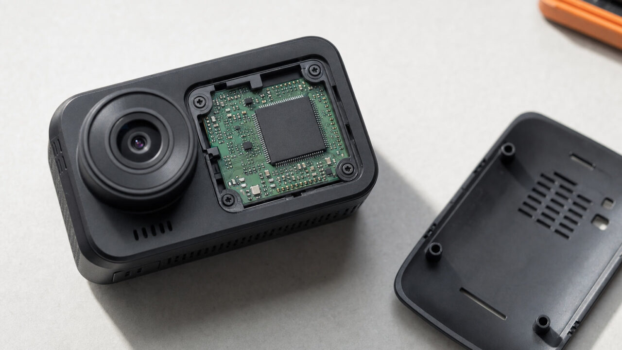 Conceptual opened dashboard camera showing its circuit board and processor on an inspection bench.