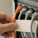 Conceptual scene of an administrator separating an orange network cable from grey patch cables while reviewing access paths.